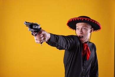 Photo of Emotional man in black Flamenco hat with gun on yellow background