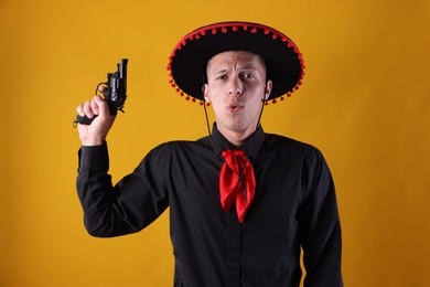 Photo of Man in black Flamenco hat with gun on yellow background