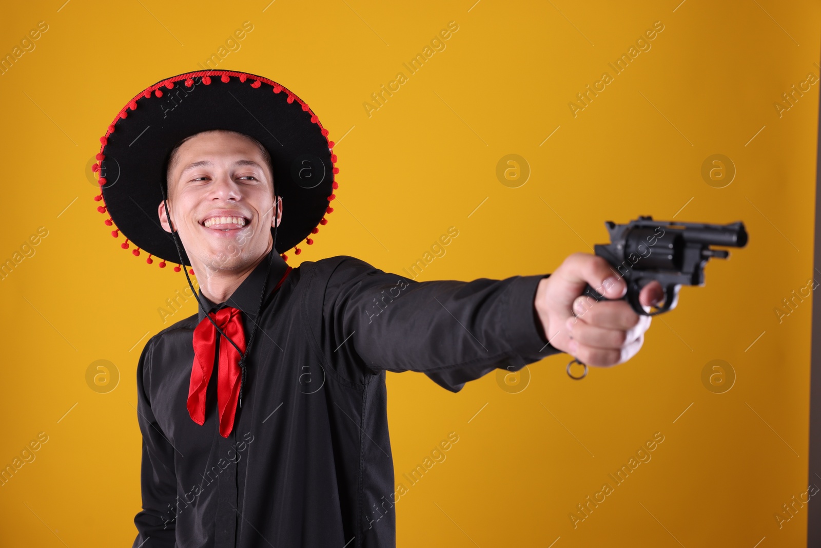 Photo of Happy man in black Flamenco hat with gun on yellow background