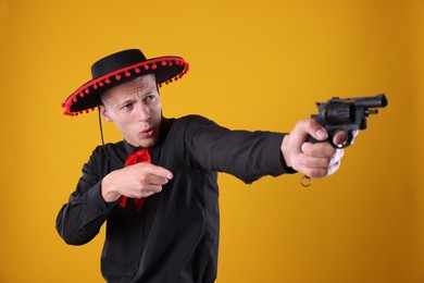 Photo of Man in black Flamenco hat with gun on yellow background