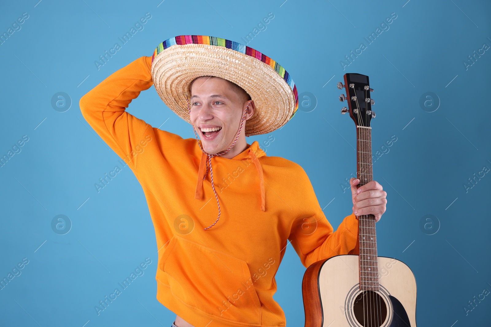 Photo of Happy man in sombrero hat with guitar on light blue background