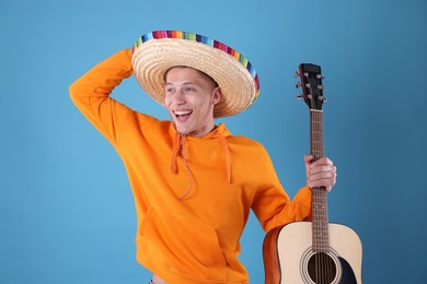 Photo of Happy man in sombrero hat with guitar on light blue background