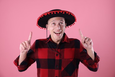 Photo of Happy man pointing at his black Flamenco hat on pink background