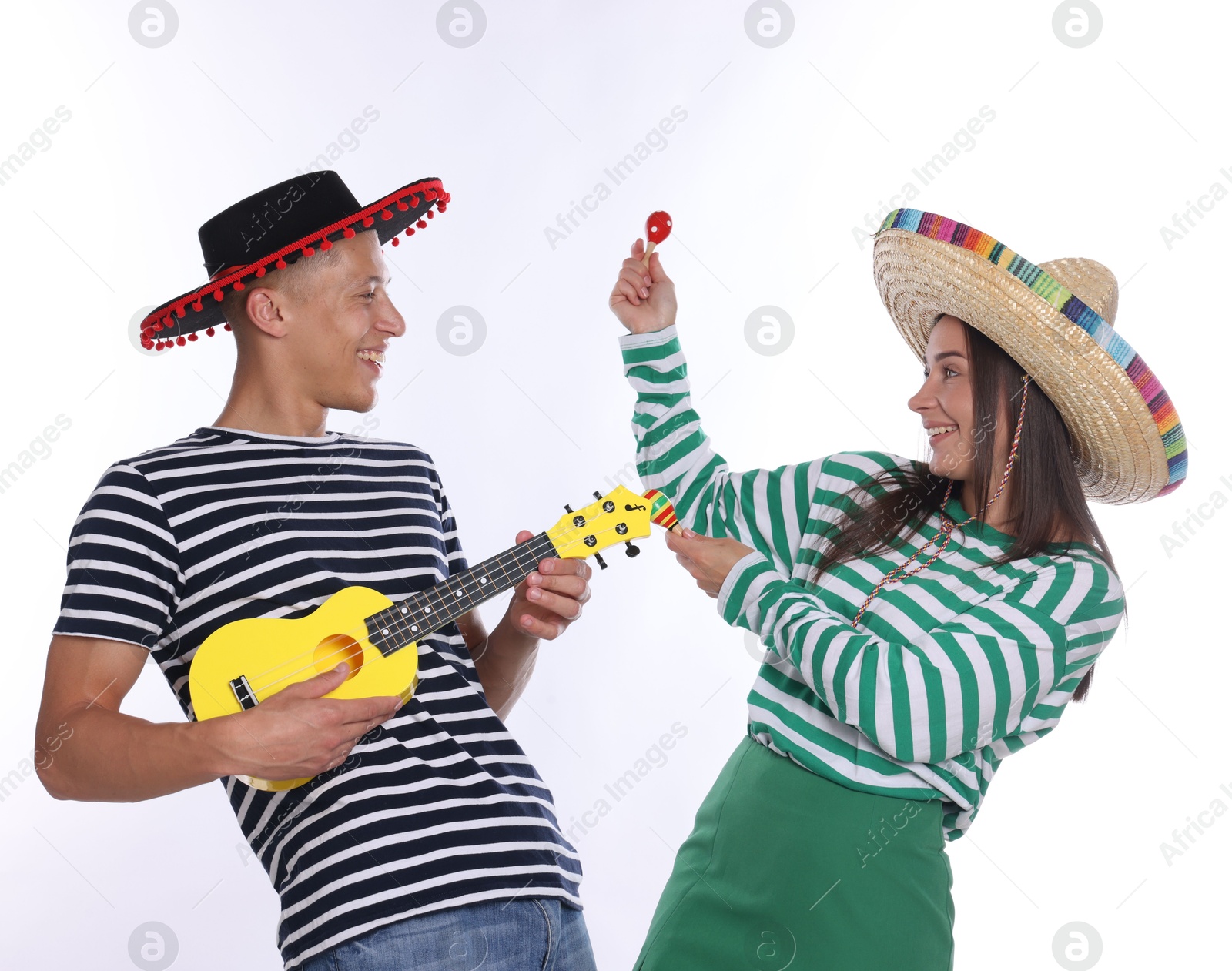 Photo of Happy couple in sombrero and Flamenco hats playing musical instruments on white background