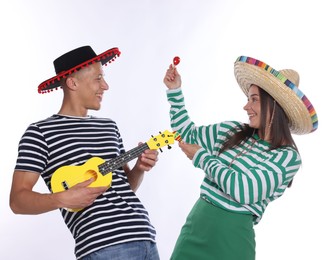 Photo of Happy couple in sombrero and Flamenco hats playing musical instruments on white background