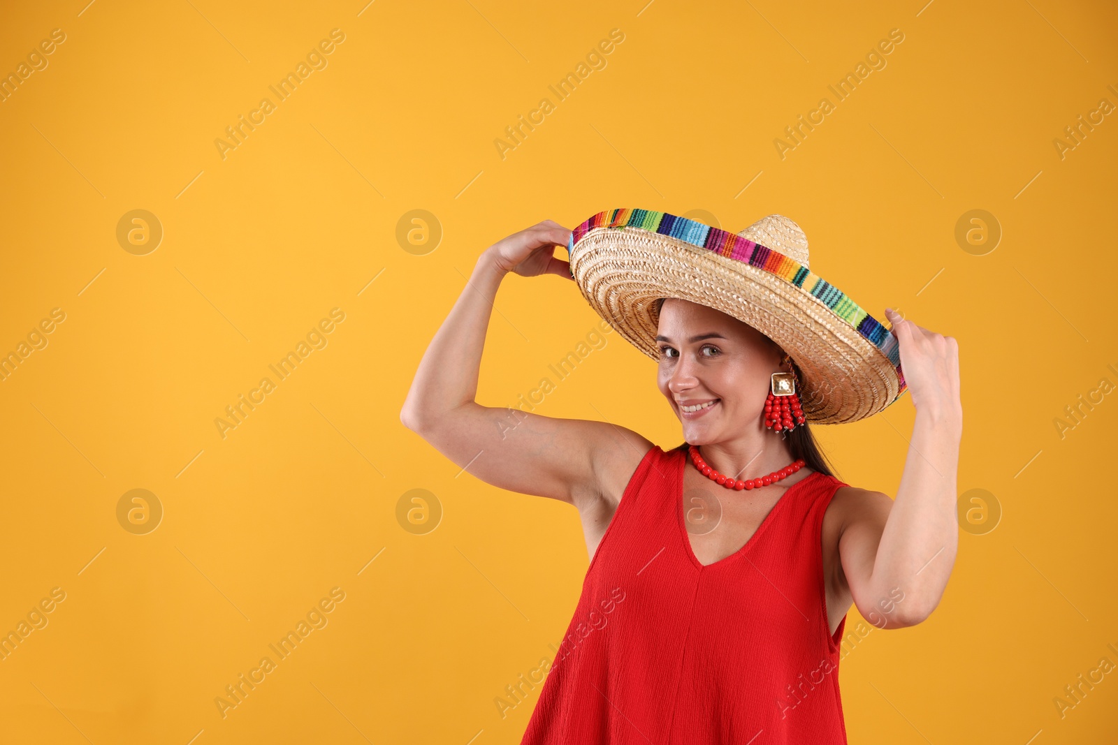 Happy woman in sombrero hat on yellow background. Space for text Photo of Happy woman in sombrero hat on yellow background. Space for text