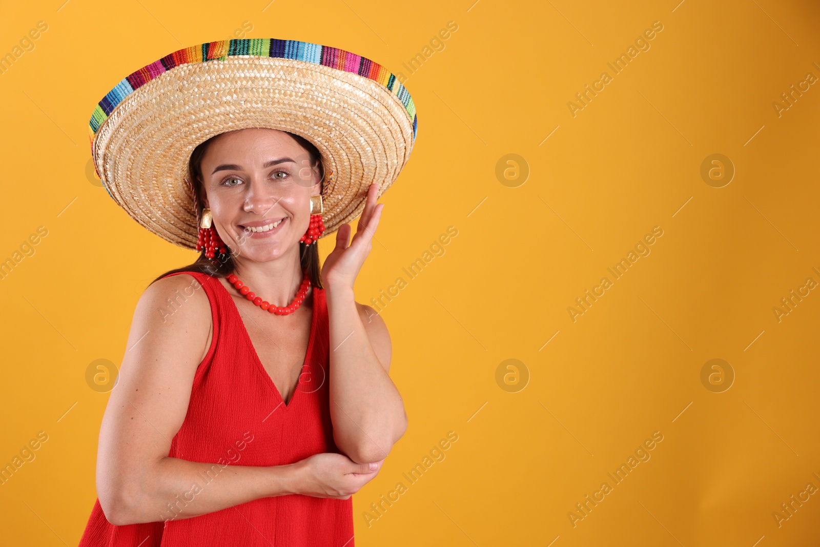 Happy woman in sombrero hat on yellow background. Space for text Photo of Happy woman in sombrero hat on yellow background. Space for text