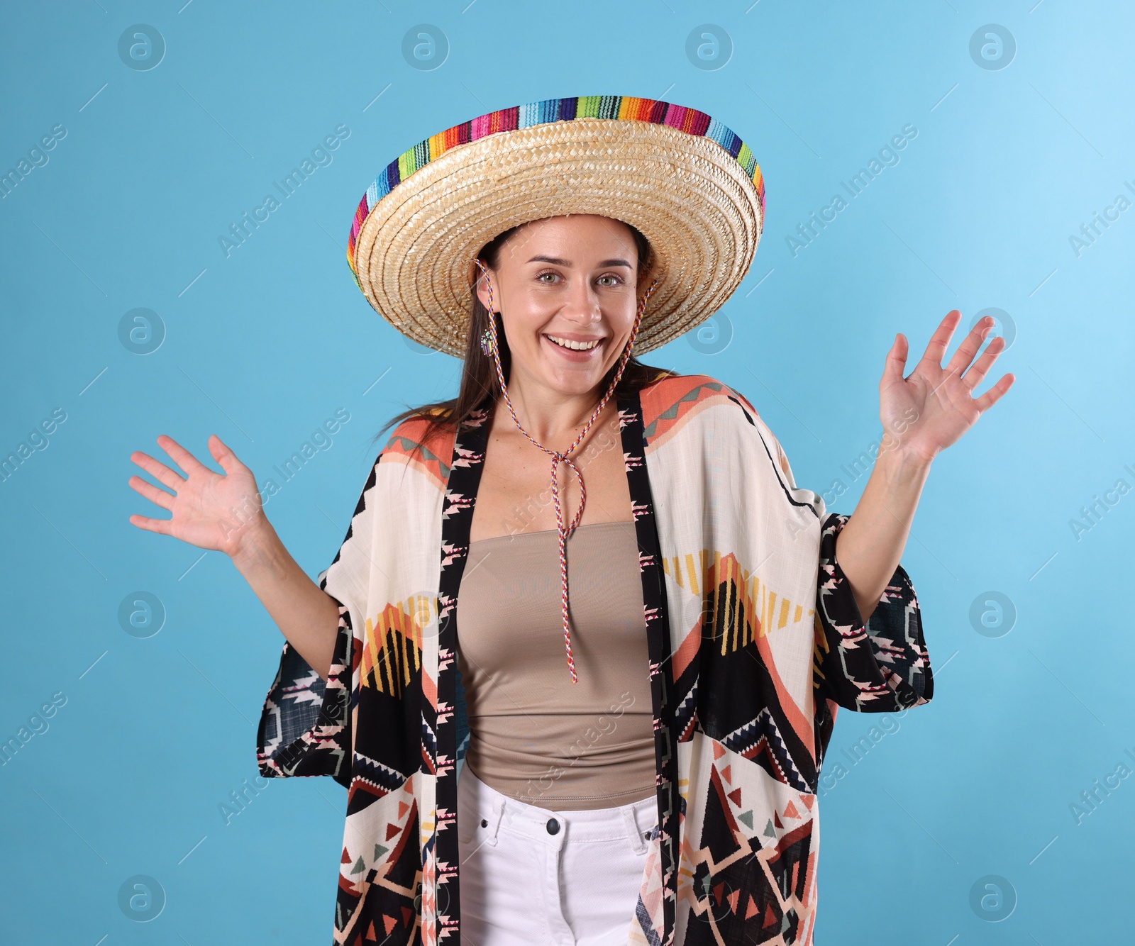 Happy woman in sombrero hat on light blue background Photo of Happy woman in sombrero hat on light blue background