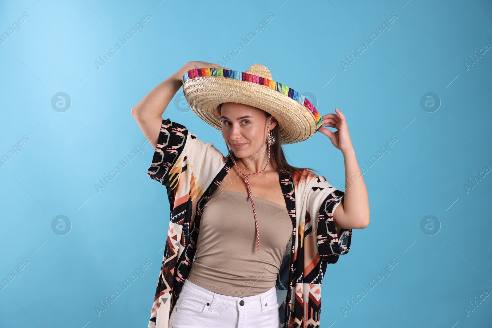 Beautiful woman in sombrero hat on light blue background Photo of Beautiful woman in sombrero hat on light blue background