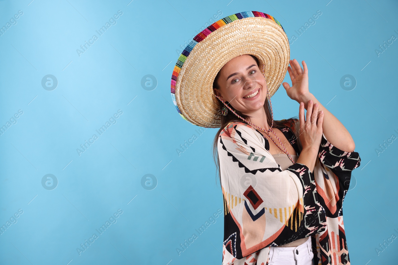 Happy woman in sombrero hat on light blue background. Space for text Photo of Happy woman in sombrero hat on light blue background. Space for text