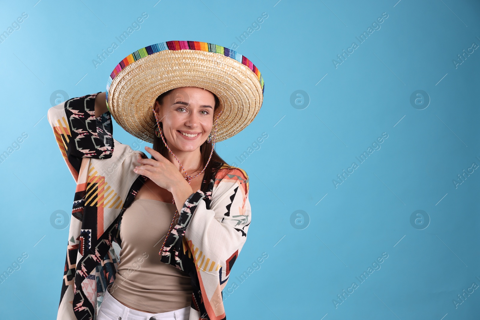 Happy woman in sombrero hat on light blue background. Space for text Photo of Happy woman in sombrero hat on light blue background. Space for text