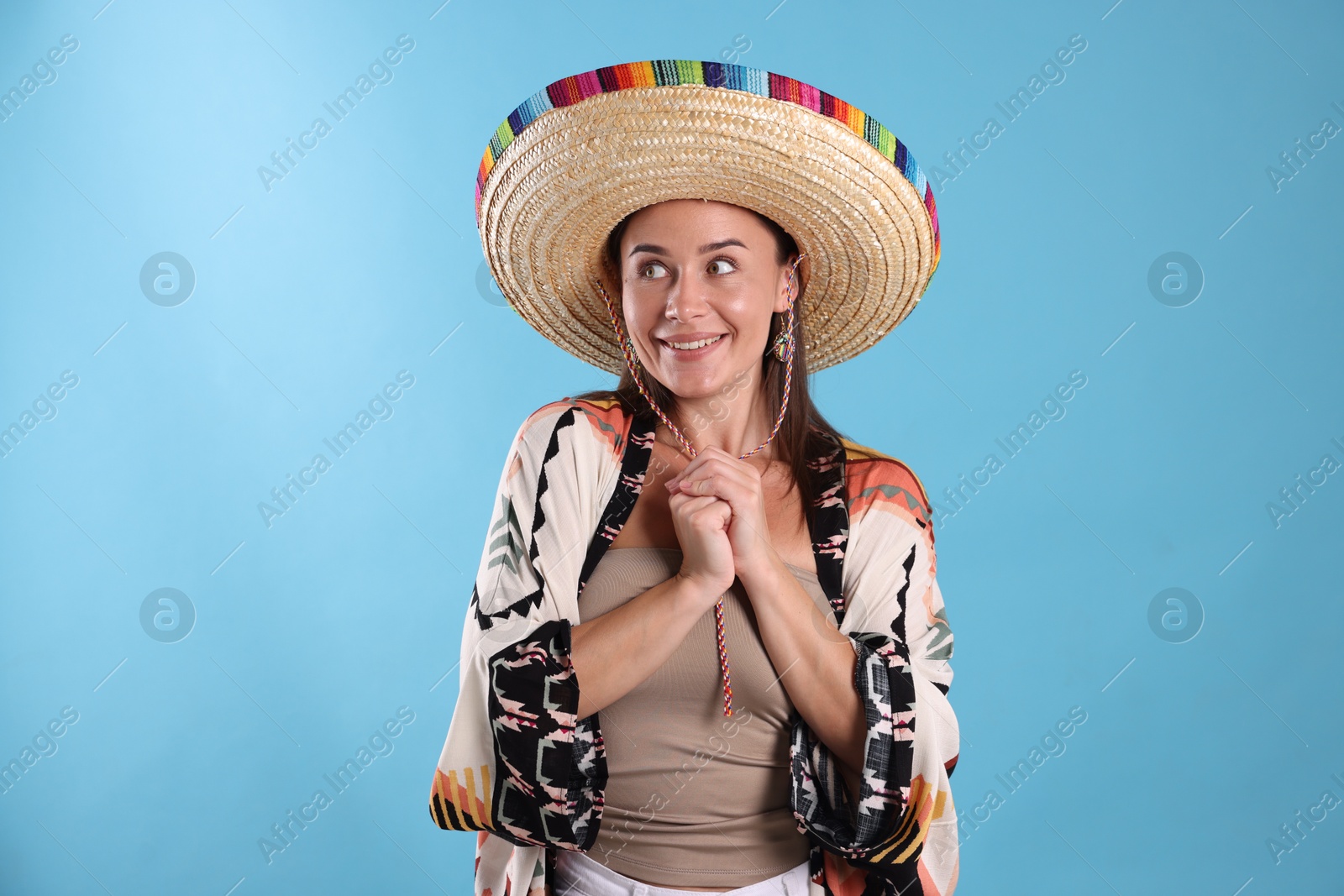 Happy woman in sombrero hat on light blue background Photo of Happy woman in sombrero hat on light blue background