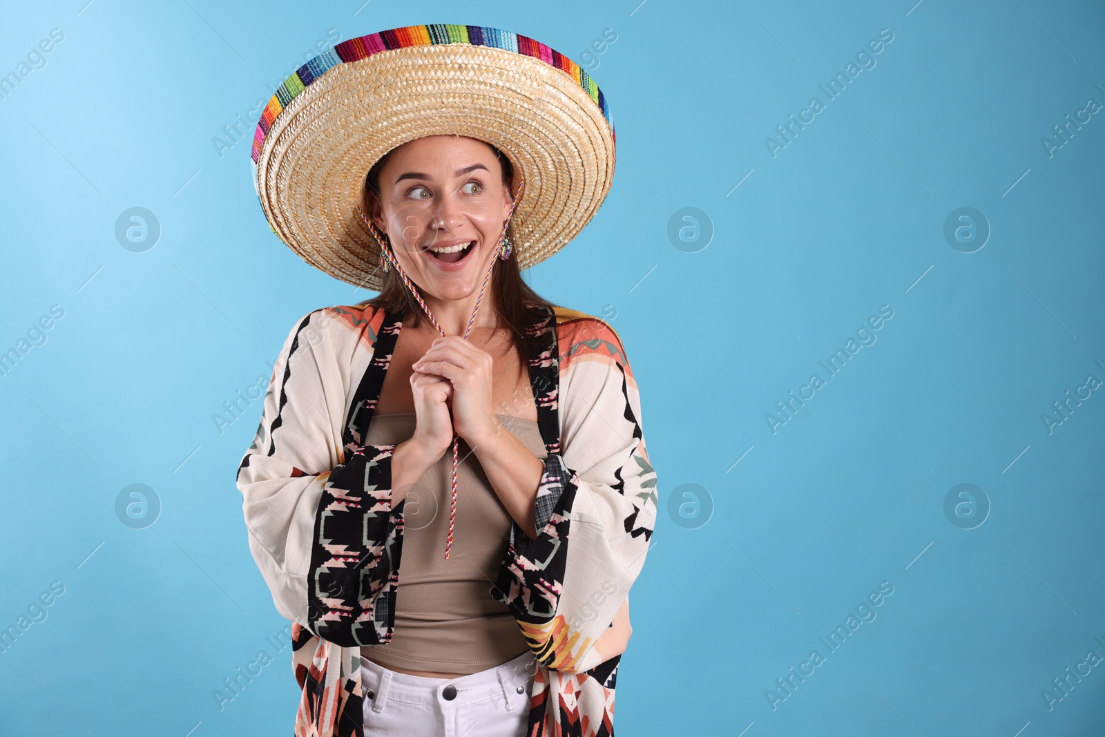 Happy woman in sombrero hat on light blue background. Space for text Photo of Happy woman in sombrero hat on light blue background. Space for text