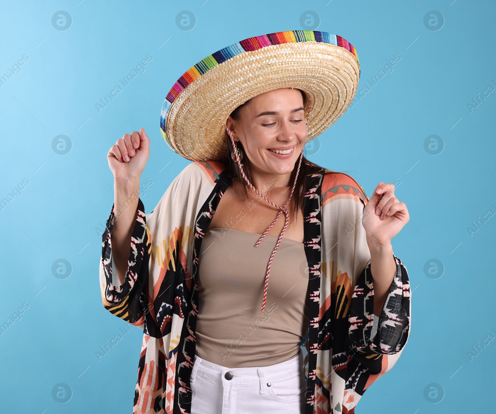Happy woman in sombrero hat on light blue background Photo of Happy woman in sombrero hat on light blue background