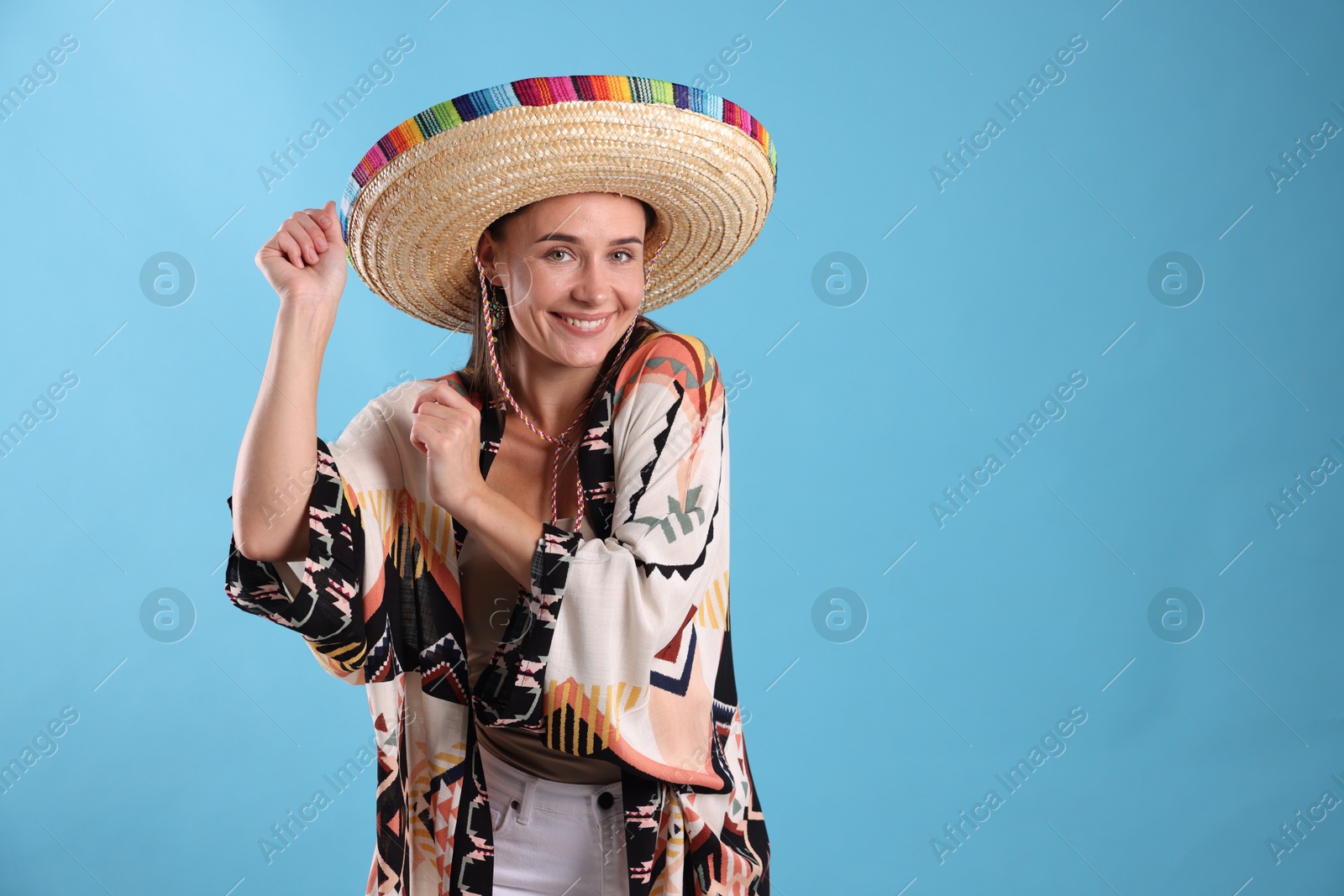 Happy woman in sombrero hat on light blue background. Space for text Photo of Happy woman in sombrero hat on light blue background. Space for text