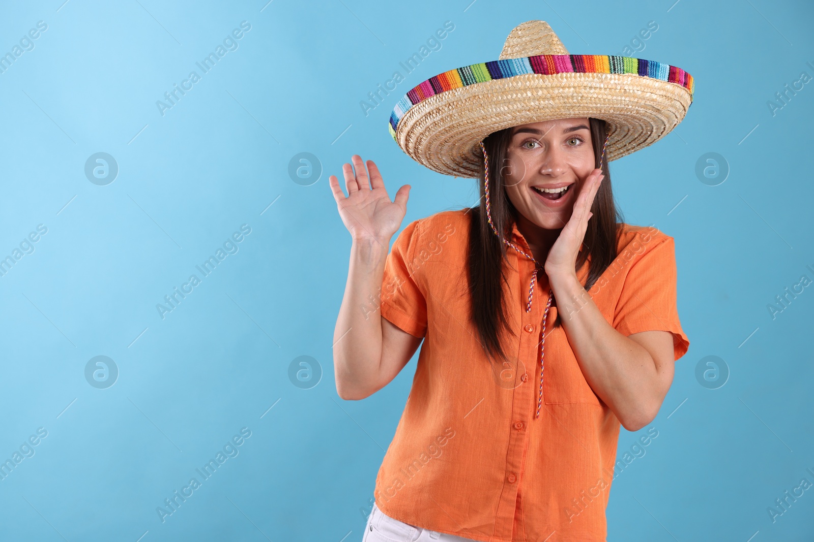 Happy woman in sombrero hat waving hello on light blue background. Space for text Photo of Happy woman in sombrero hat waving hello on light blue background. Space for text