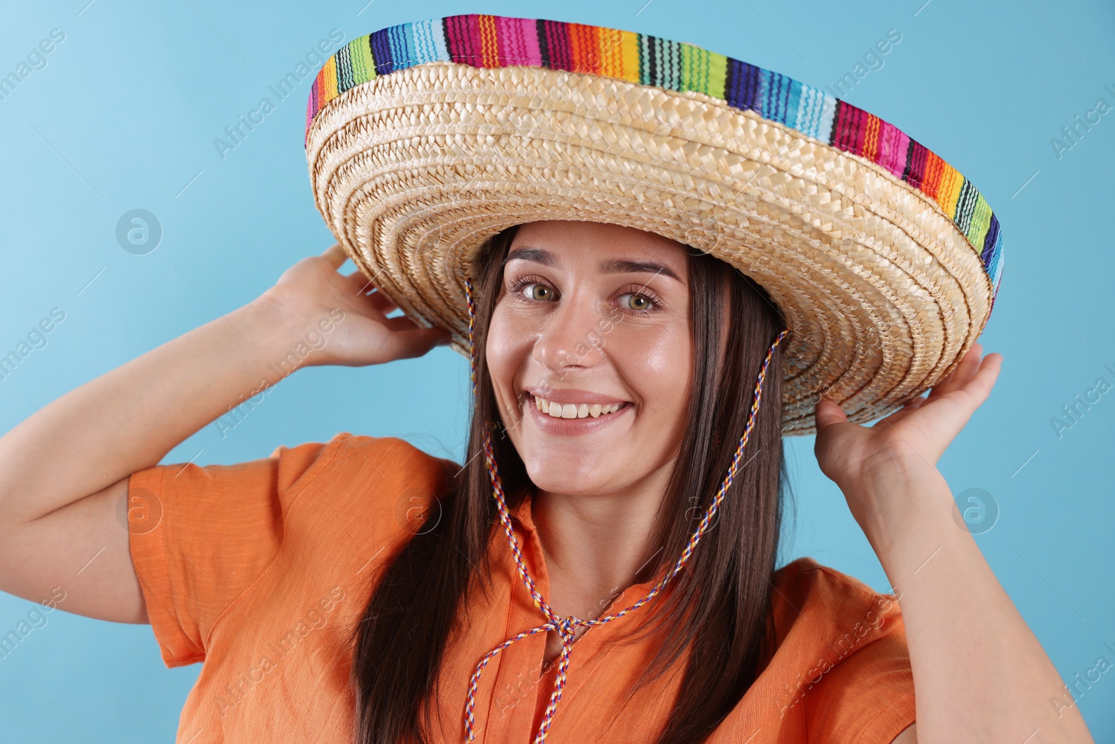Happy woman in sombrero hat on light blue background Photo of Happy woman in sombrero hat on light blue background