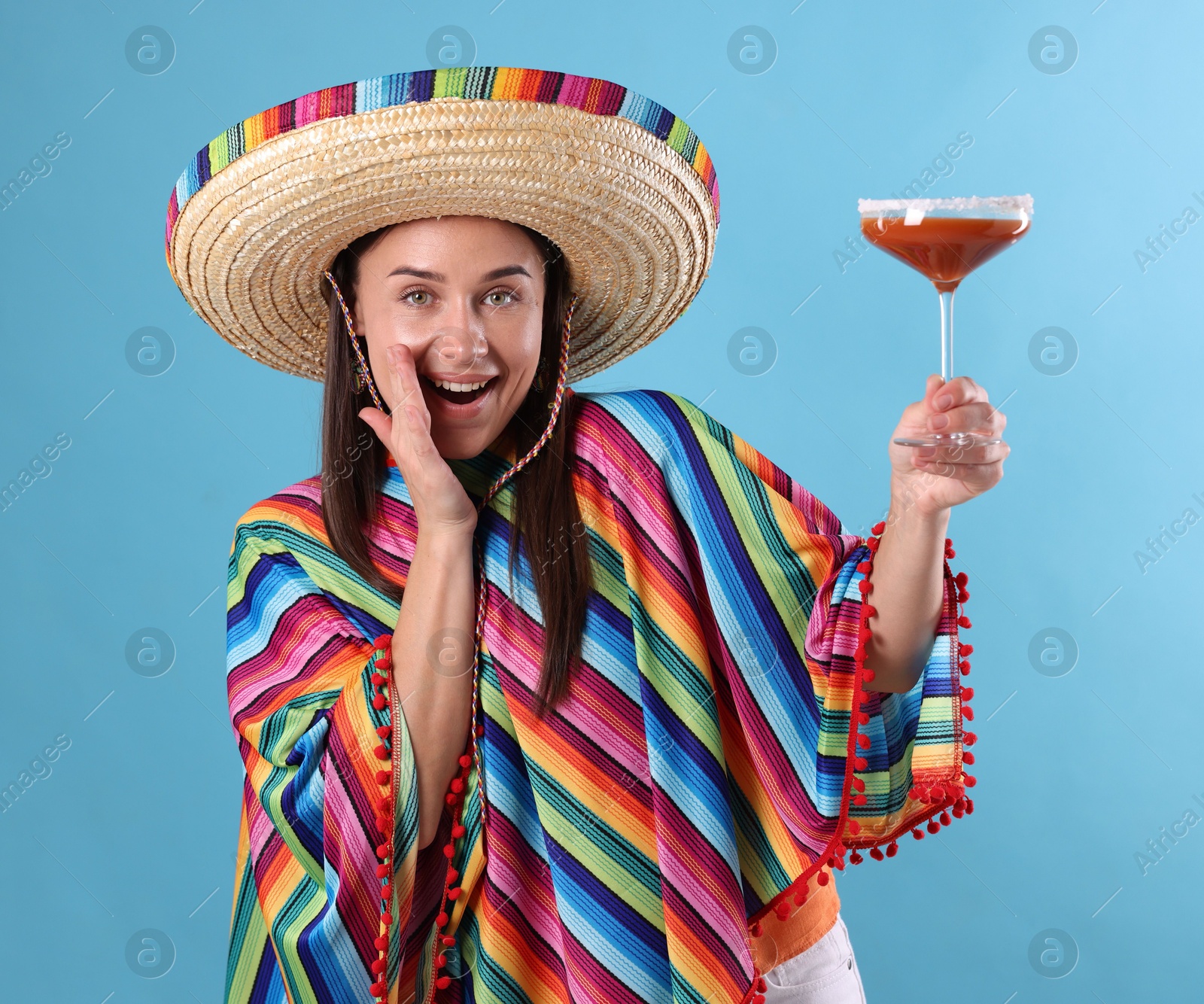 Photo of Smiling woman in sombrero hat with cocktail on light blue background