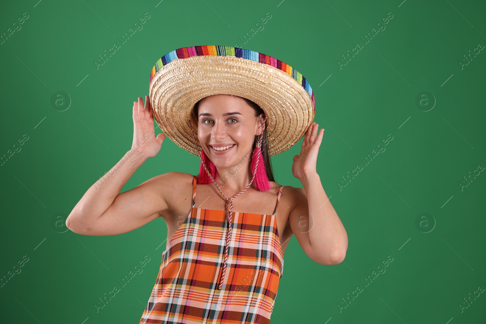 Smiling woman in sombrero hat on green background Photo of Smiling woman in sombrero hat on green background