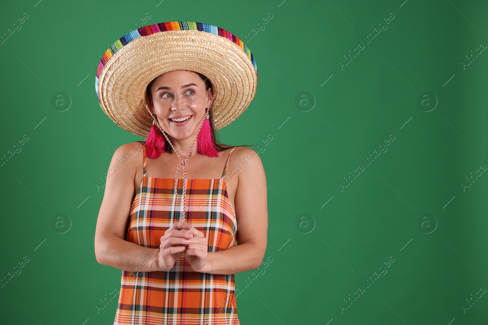 Smiling woman in sombrero hat on green background. Space for text Photo of Smiling woman in sombrero hat on green background. Space for text