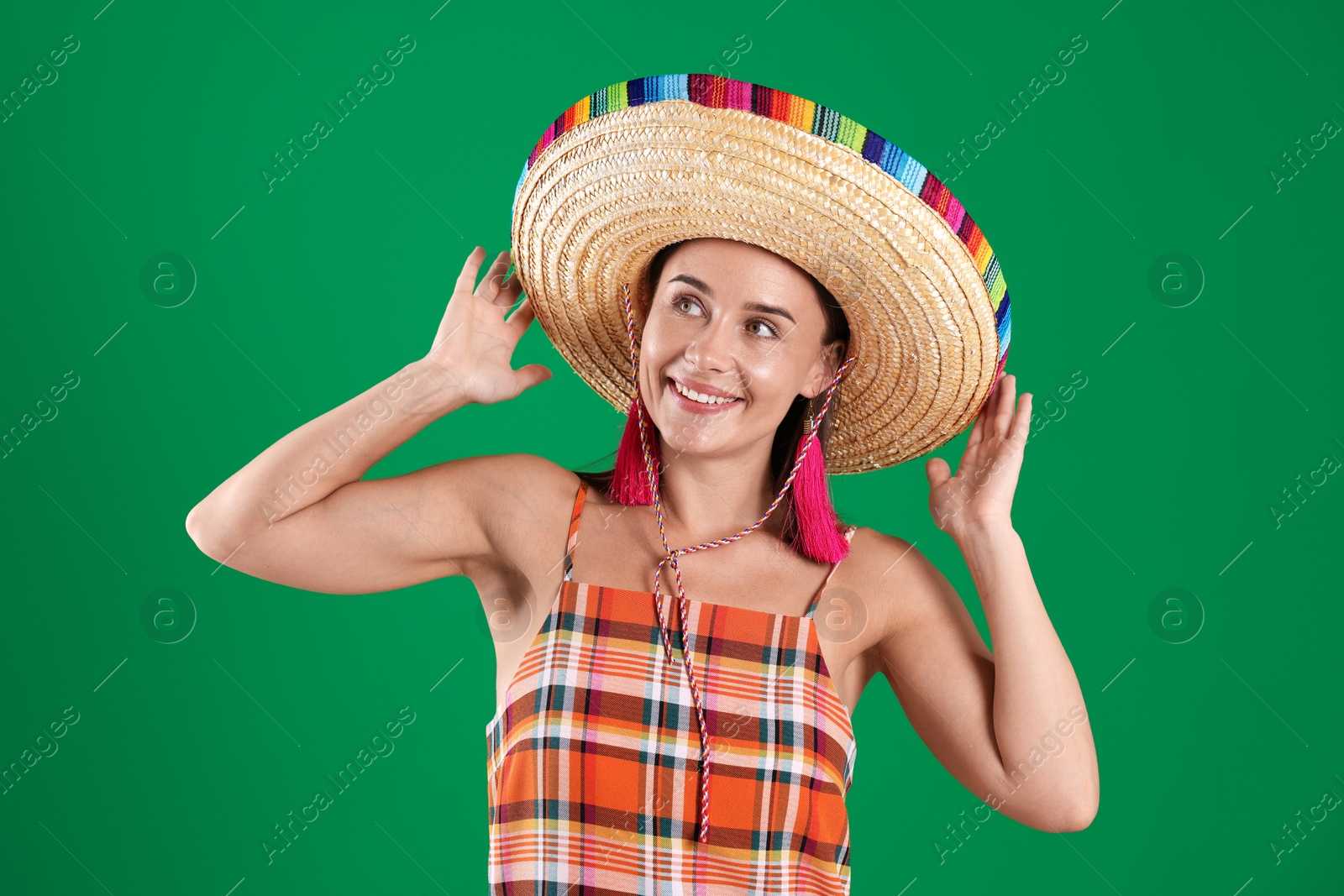 Smiling woman in sombrero hat on green background Photo of Smiling woman in sombrero hat on green background