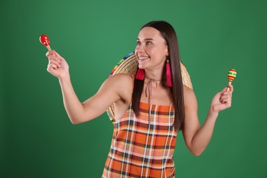 Photo of Smiling woman with sombrero hat playing maracas on green background