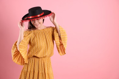 Photo of Smiling woman in black Flamenco hat and dress on pink background. Space for text