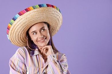 Photo of Smiling woman in sombrero hat on violet background. Space for text