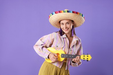Photo of Smiling woman in sombrero hat playing ukulele on violet background