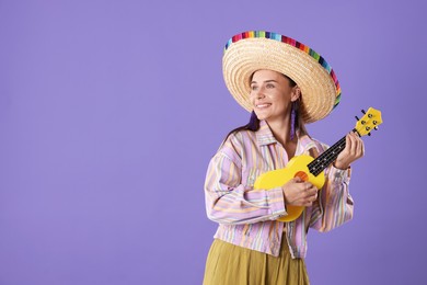 Photo of Smiling woman in sombrero hat playing ukulele on violet background. Space for text