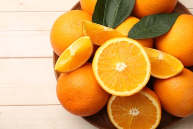 Photo of Fresh ripe oranges and leaves on light wooden table, top view. Space for text