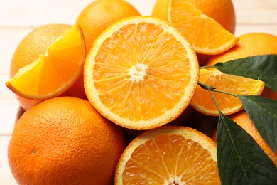 Photo of Fresh ripe oranges and leaves on light table, closeup