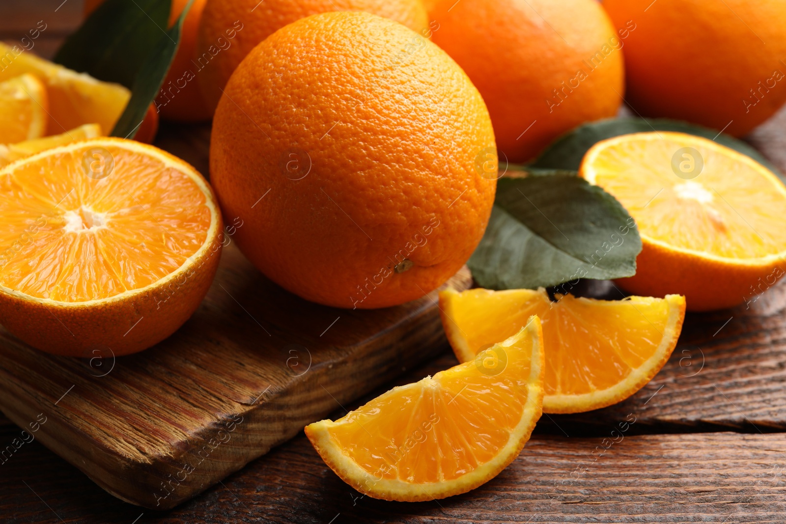 Fresh ripe oranges and leaves on wooden table, closeup Photo of Fresh ripe oranges and leaves on wooden table, closeup