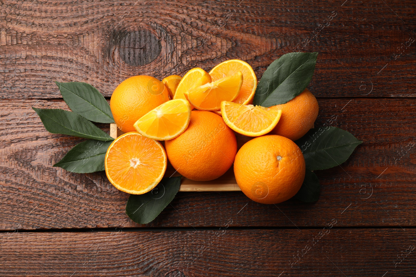 Fresh ripe oranges and leaves on wooden table, top view Photo of Fresh ripe oranges and leaves on wooden table, top view