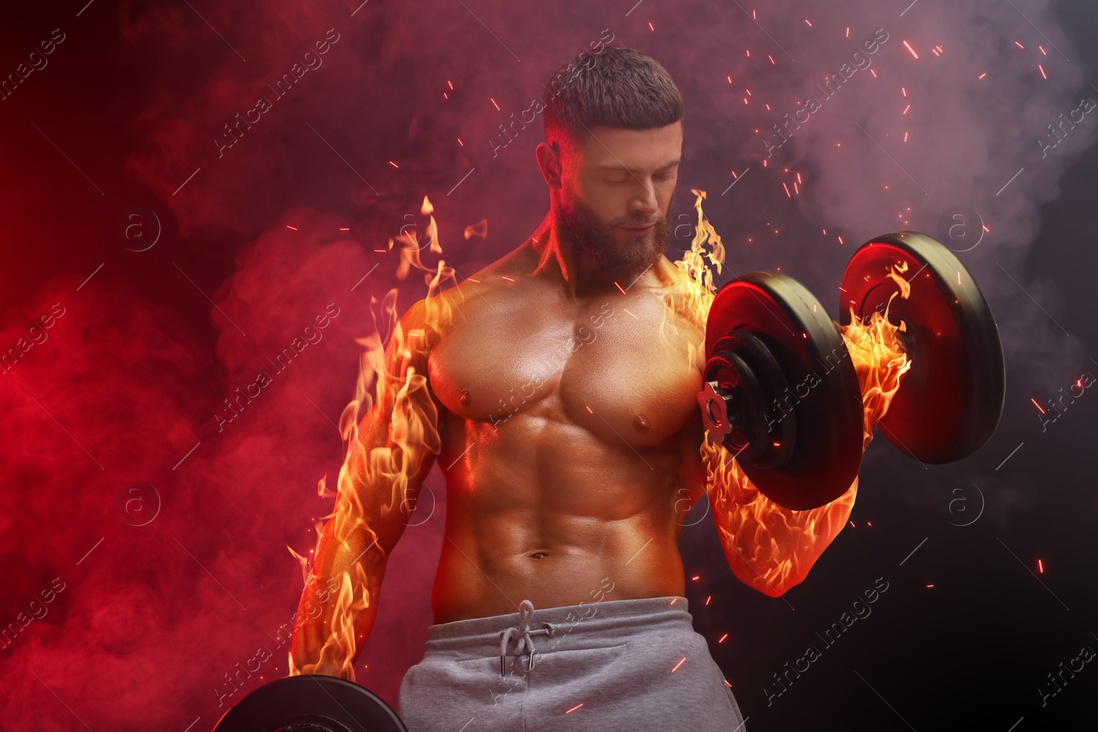 Image of Bodybuilder exercising with dumbbells in smoke against dark background. Muscular man with flaming arms