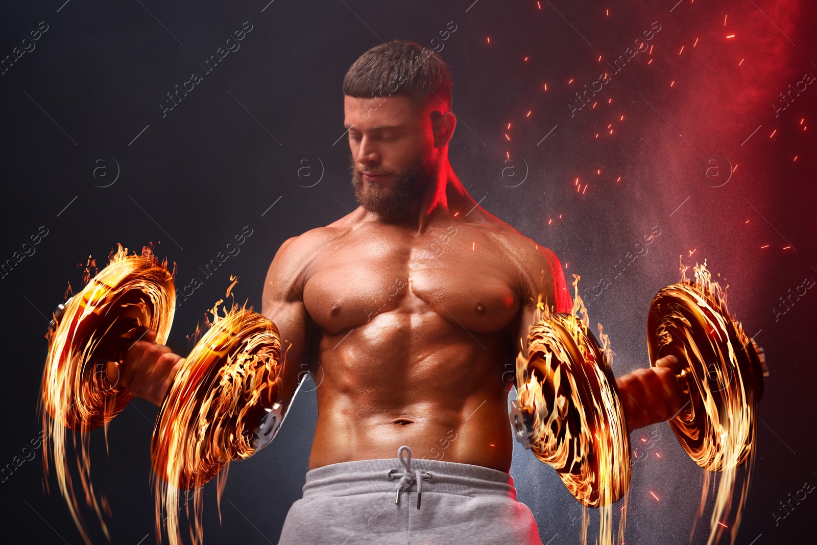 Image of Bodybuilder exercising with flaming dumbbells in smoke against dark background