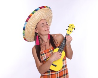 Photo of Beautiful woman in sombrero hat playing ukulele on white background