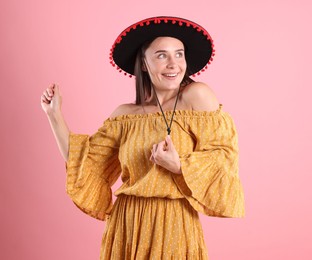 Photo of Smiling woman in black Flamenco hat and dress dancing on pink background