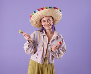 Photo of Smiling woman in sombrero hat playing maracas on violet background