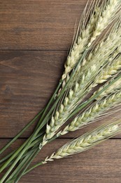 Photo of Green wheat spikes on wooden table, flat lay