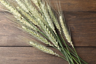 Photo of Green wheat spikes on wooden table, flat lay