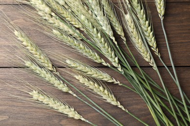 Photo of Green wheat spikes on wooden table, flat lay