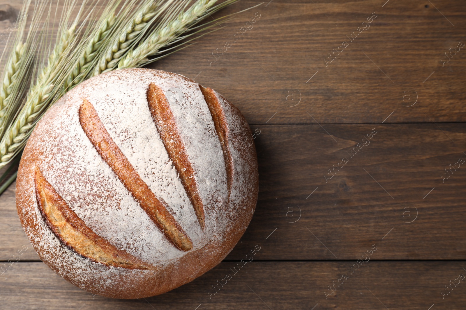Fresh bread and green wheat spikes on wooden table, flat lay. Space for text Photo of Fresh bread and green wheat spikes on wooden table, flat lay. Space for text
