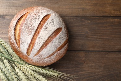 Photo of Fresh bread and green wheat spikes on wooden table, flat lay. Space for text