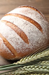 Photo of Fresh bread and green wheat spikes on table, closeup