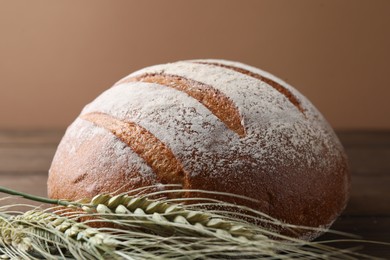 Photo of Fresh bread and green wheat spikes on table, closeup