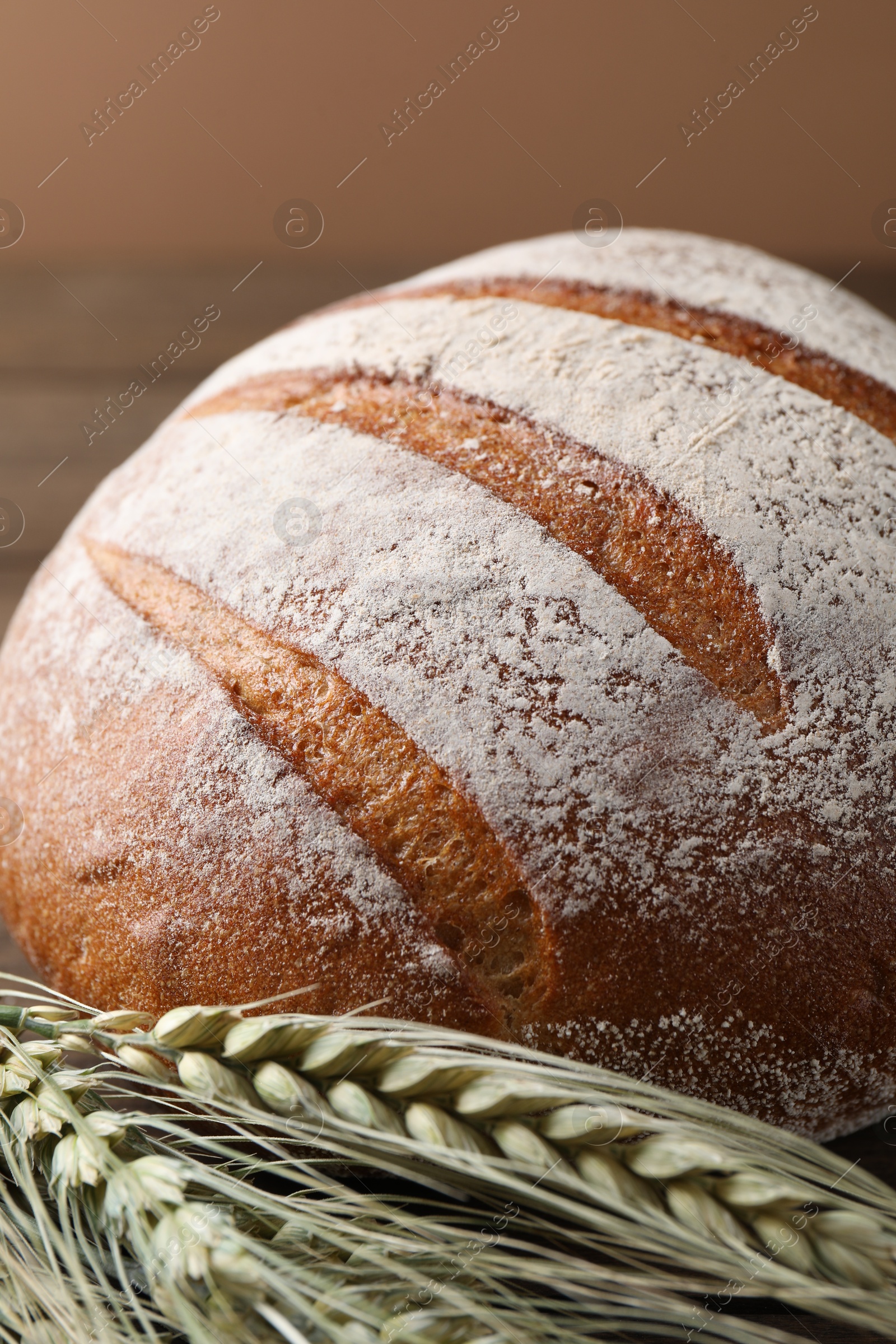 Photo of Fresh bread and green wheat spikes on table, closeup