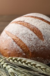 Photo of Fresh bread and green wheat spikes on table, closeup