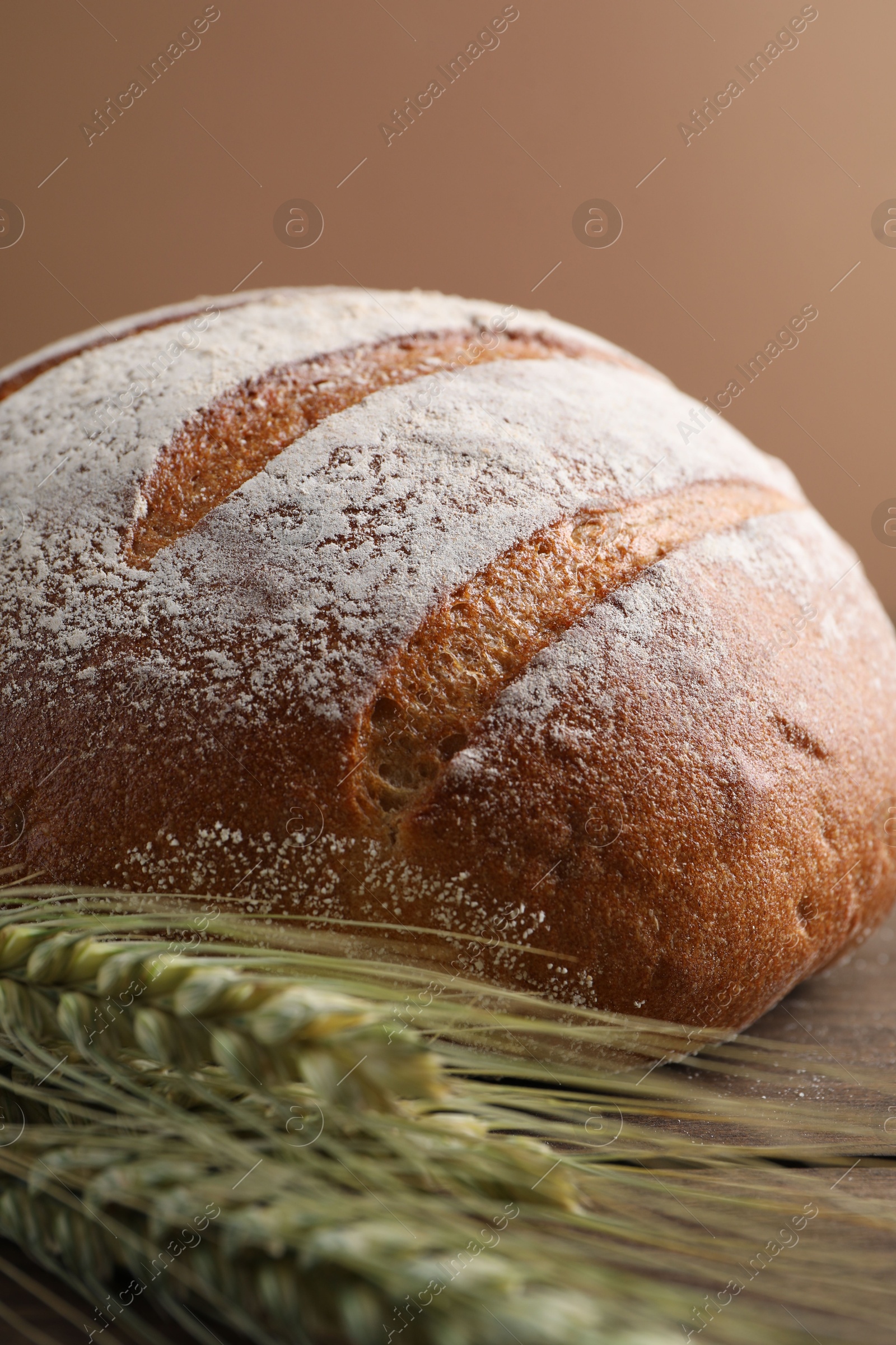 Photo of Fresh bread and green wheat spikes on table, closeup