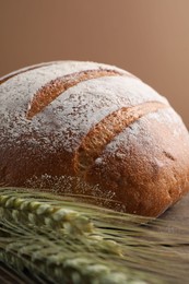 Photo of Fresh bread and green wheat spikes on table, closeup